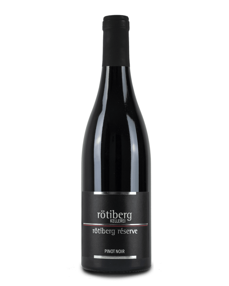 Rötiberg Kellerei Pinot Noir Lage Reserve 2019 Rotwein in einem Glas, dunkle Rotweinfarbe, Weinflasche im Hintergrund